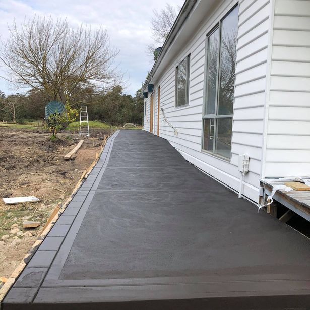 Newly finished concrete path beside a house in the process of drying
